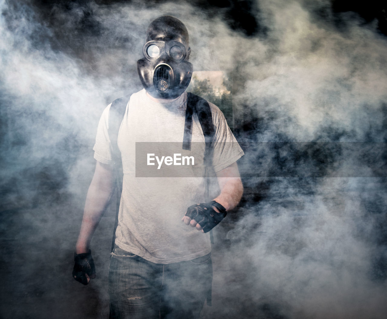 Man wearing gas mask standing under bridge