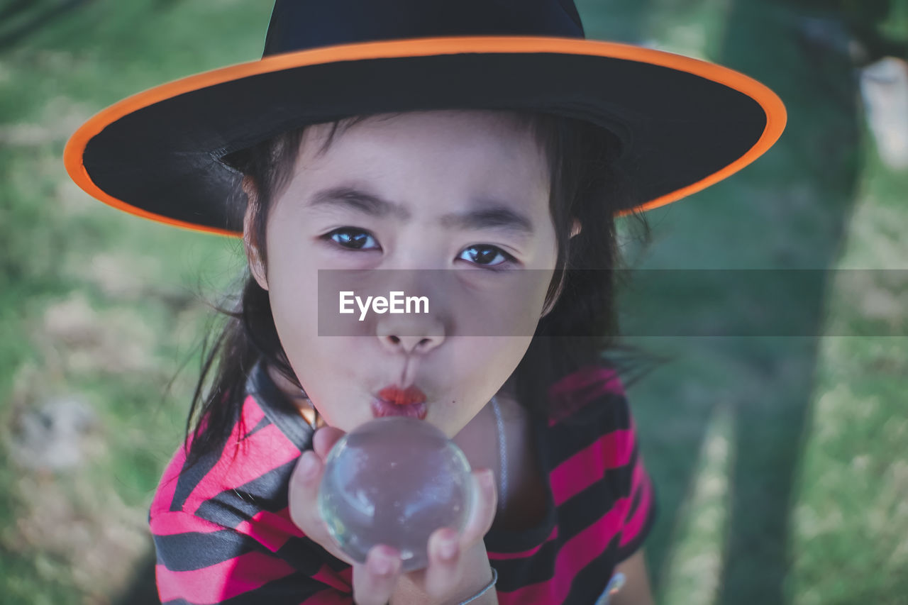 Portrait of girl wearing witch hat holding crystal ball