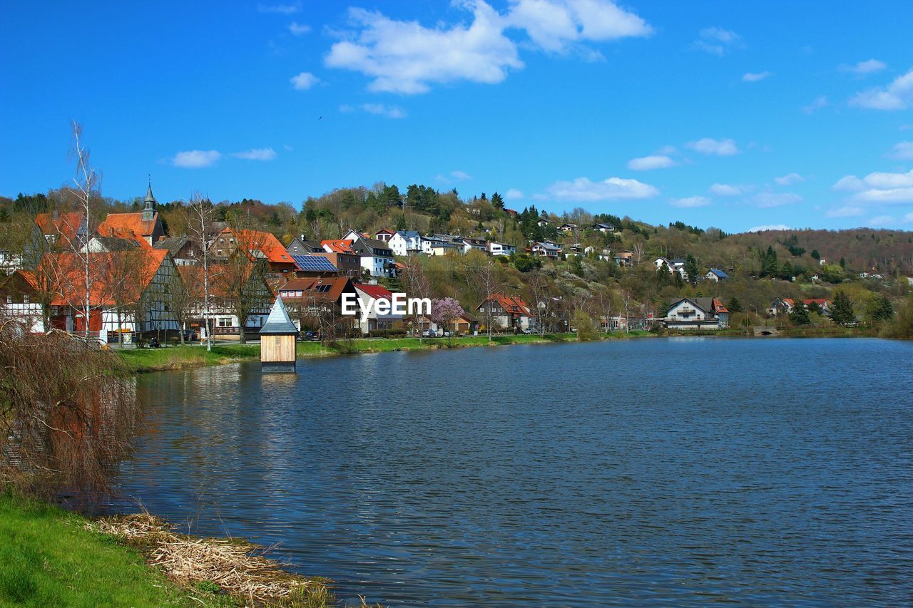 Village by lake against sky