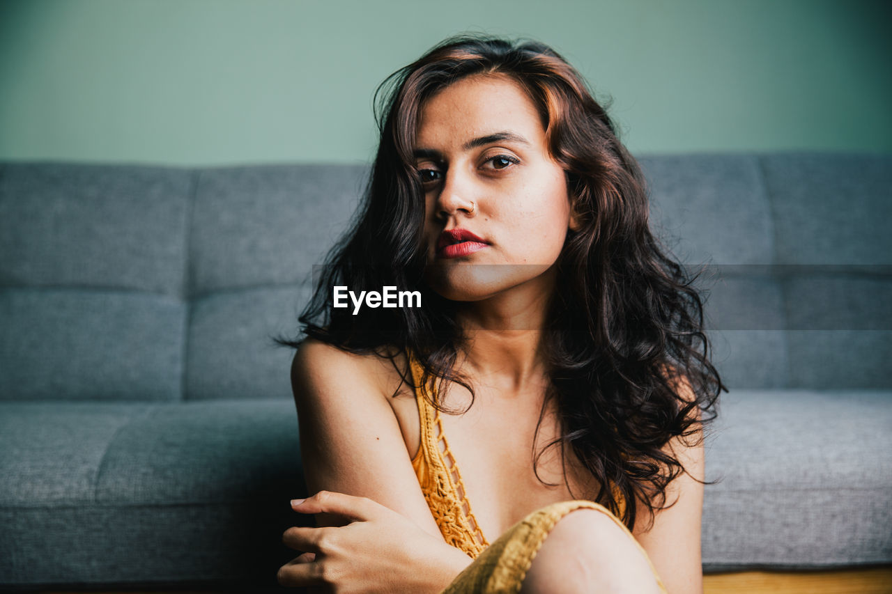 PORTRAIT OF A BEAUTIFUL YOUNG WOMAN SITTING IN CORRIDOR