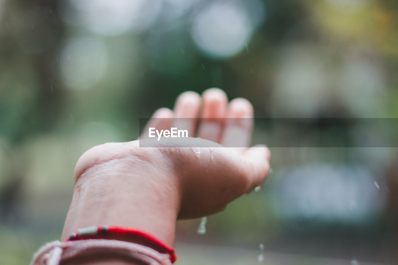 Close-up of hand catching raindrops outdoors