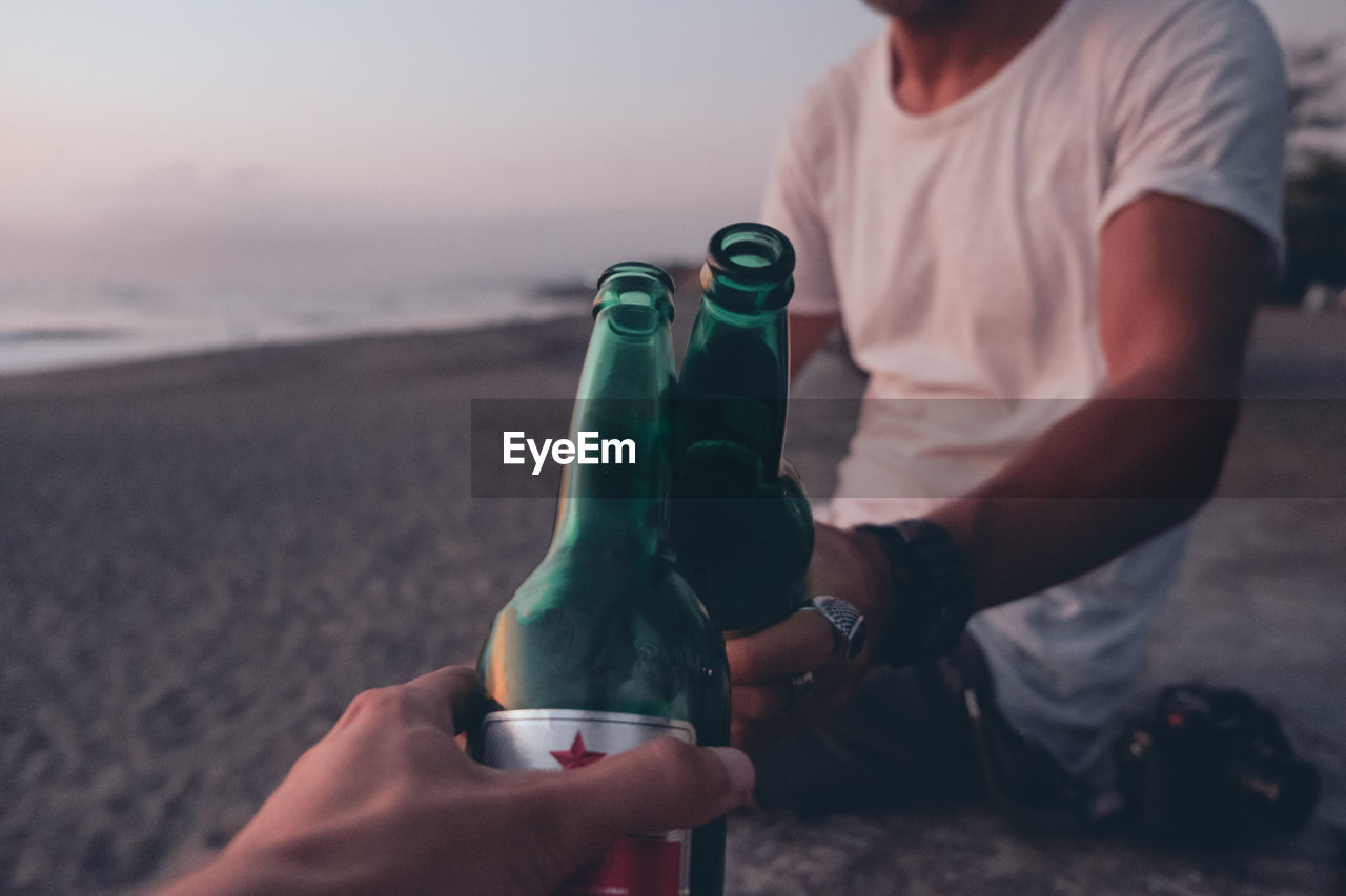 Friends toasting with beer on sunset beach