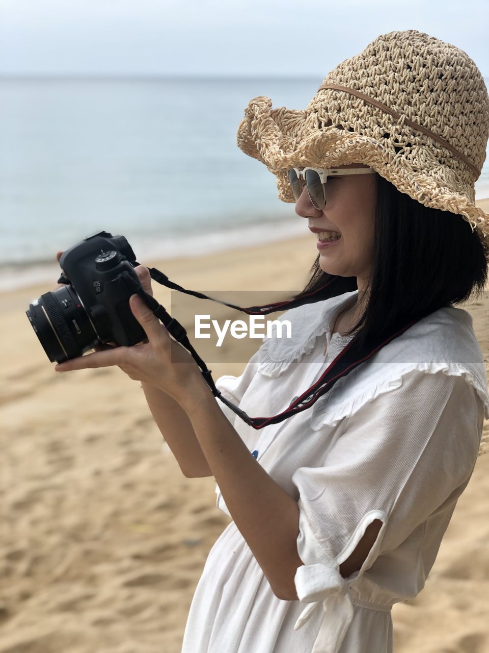 Midsection of woman holding camera at beach