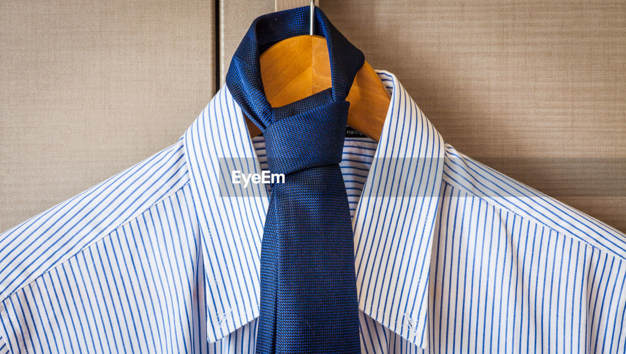 Close-up of shirt with necktie hanging on coathanger by window
