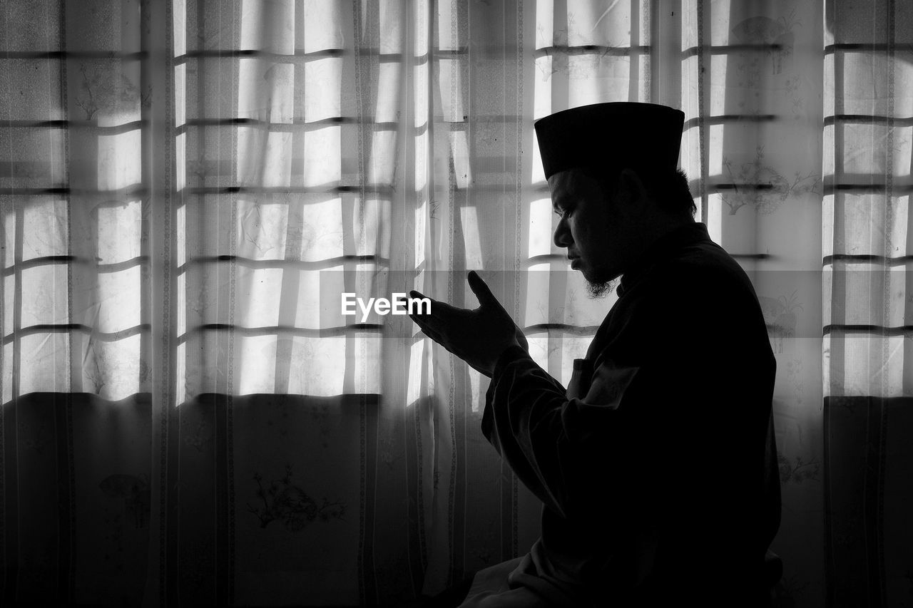 Side view of an praying in darkroom