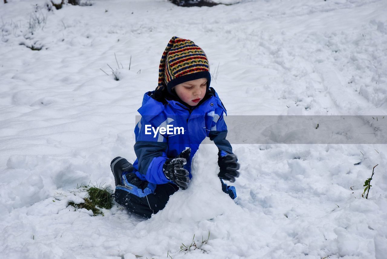 A boy sitting on snow covered land