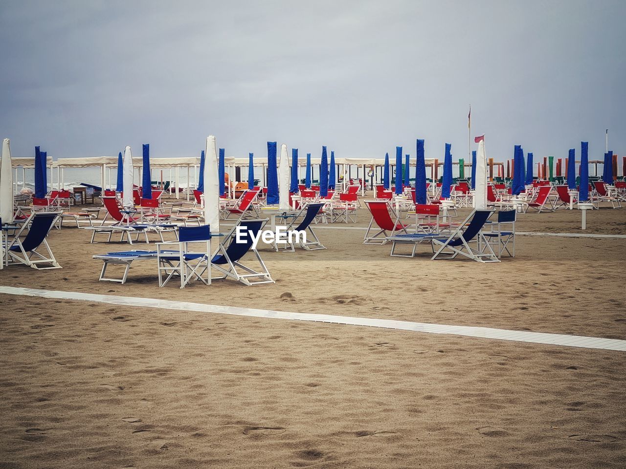 LOUNGE CHAIRS ON BEACH AGAINST SKY