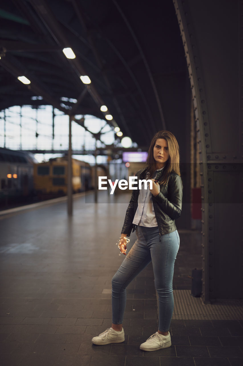 Portrait of young woman standing at railroad station platform