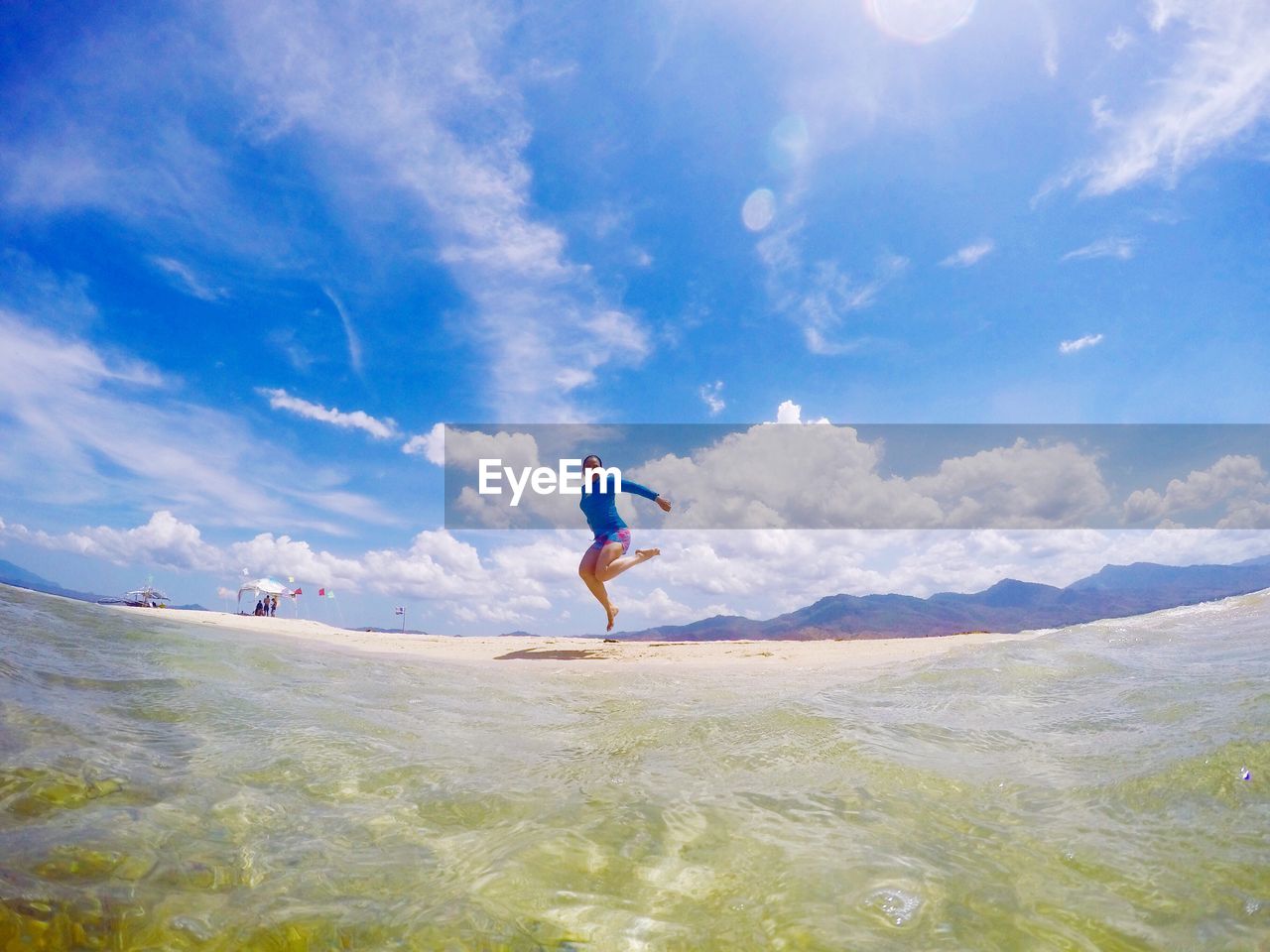 Full length of woman jumping on shore at beach