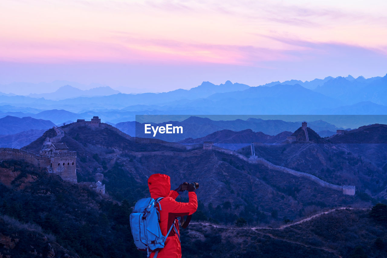 Man photographing great wall of china on mountain against sky