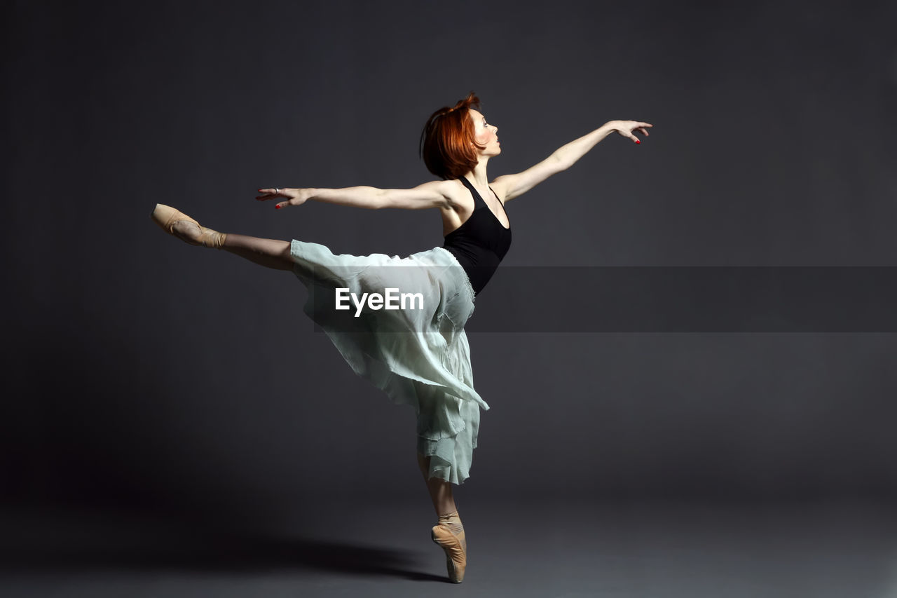 Ballerina dancing against gray backdrop