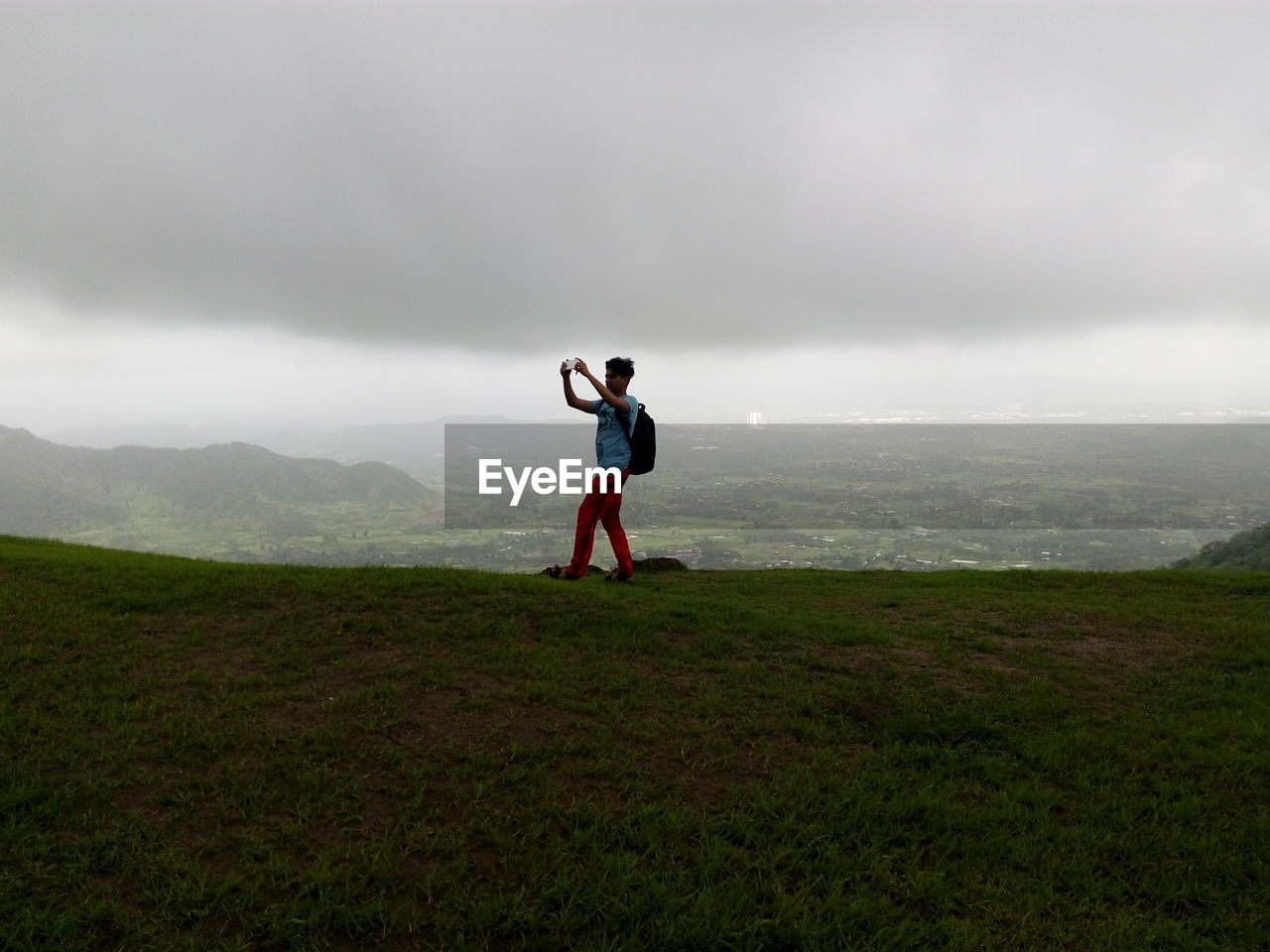 Man standing on mountain against cloudy sky