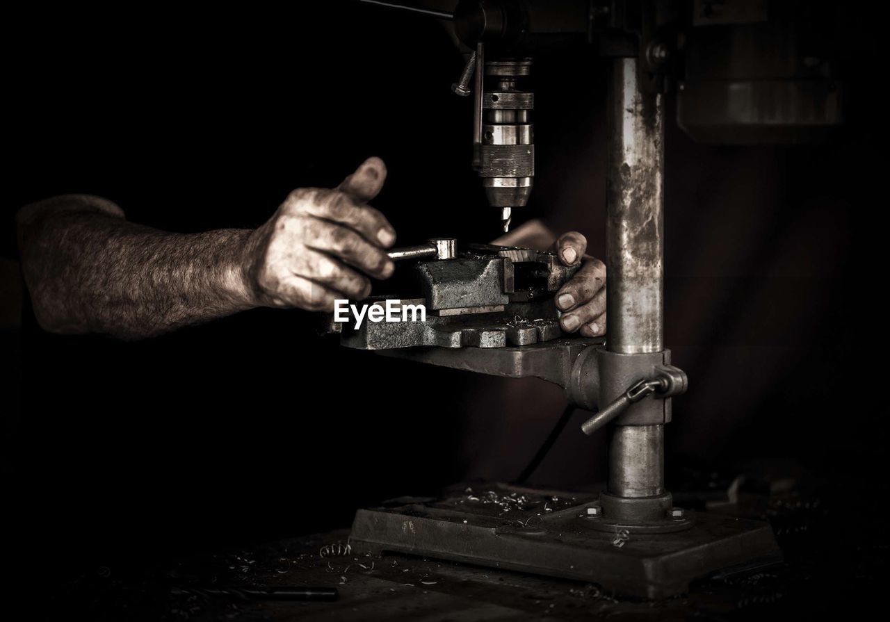 Midsection of man operating machinery in darkroom