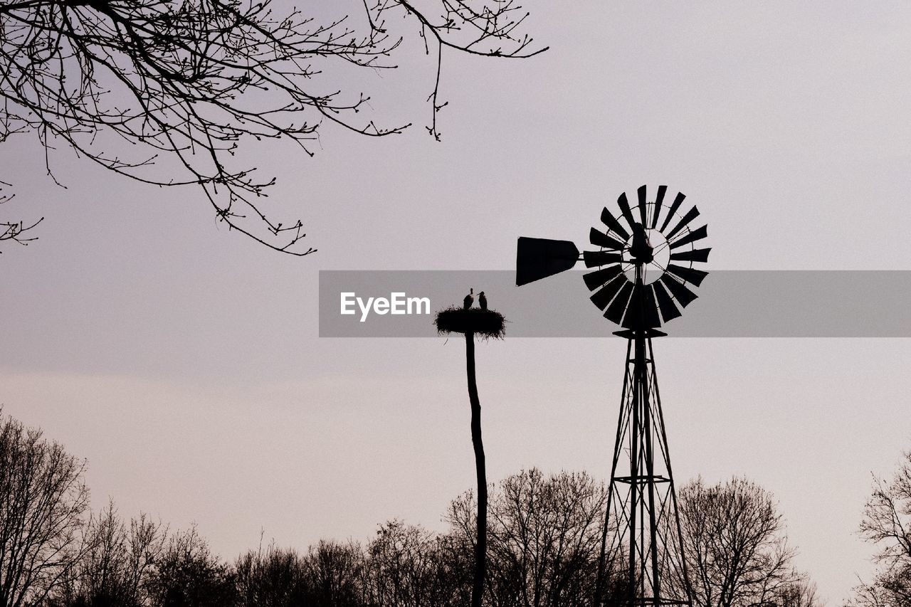 LOW ANGLE VIEW OF SILHOUETTE TRADITIONAL WINDMILL ON FIELD AGAINST SKY