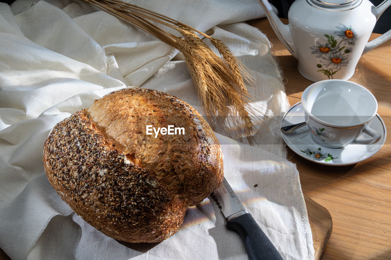 food and drink, food, bread, freshness, table, breakfast, cup, baked, drink, high angle view, healthy eating, mug, wellbeing, indoors, meal, no people, still life, eating utensil, hot drink, refreshment, cereal plant, wood, tea, coffee, loaf of bread, kitchen utensil, brown, morning, close-up