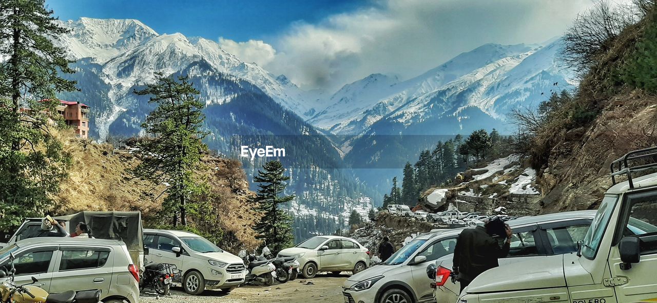 CARS ON ROAD AGAINST SNOWCAPPED MOUNTAINS