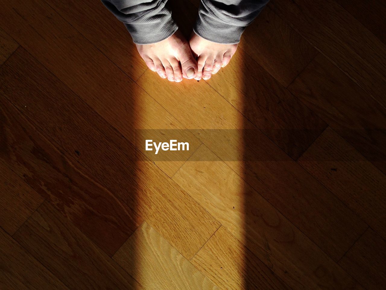 Sunlight falling on legs of person standing at floor