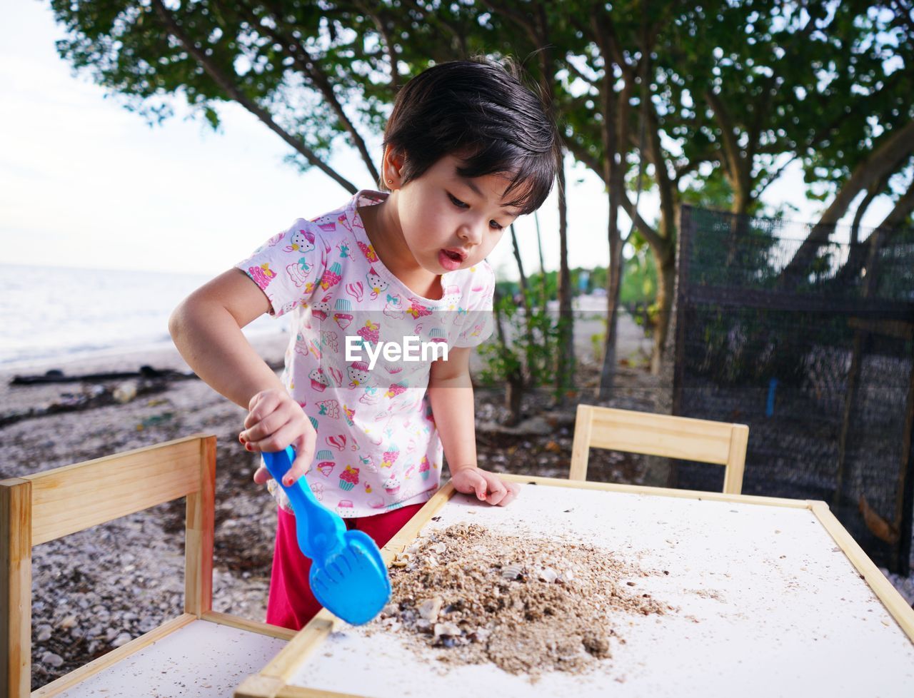 Girl are playing in the sand on a table against the backdrop of the beach