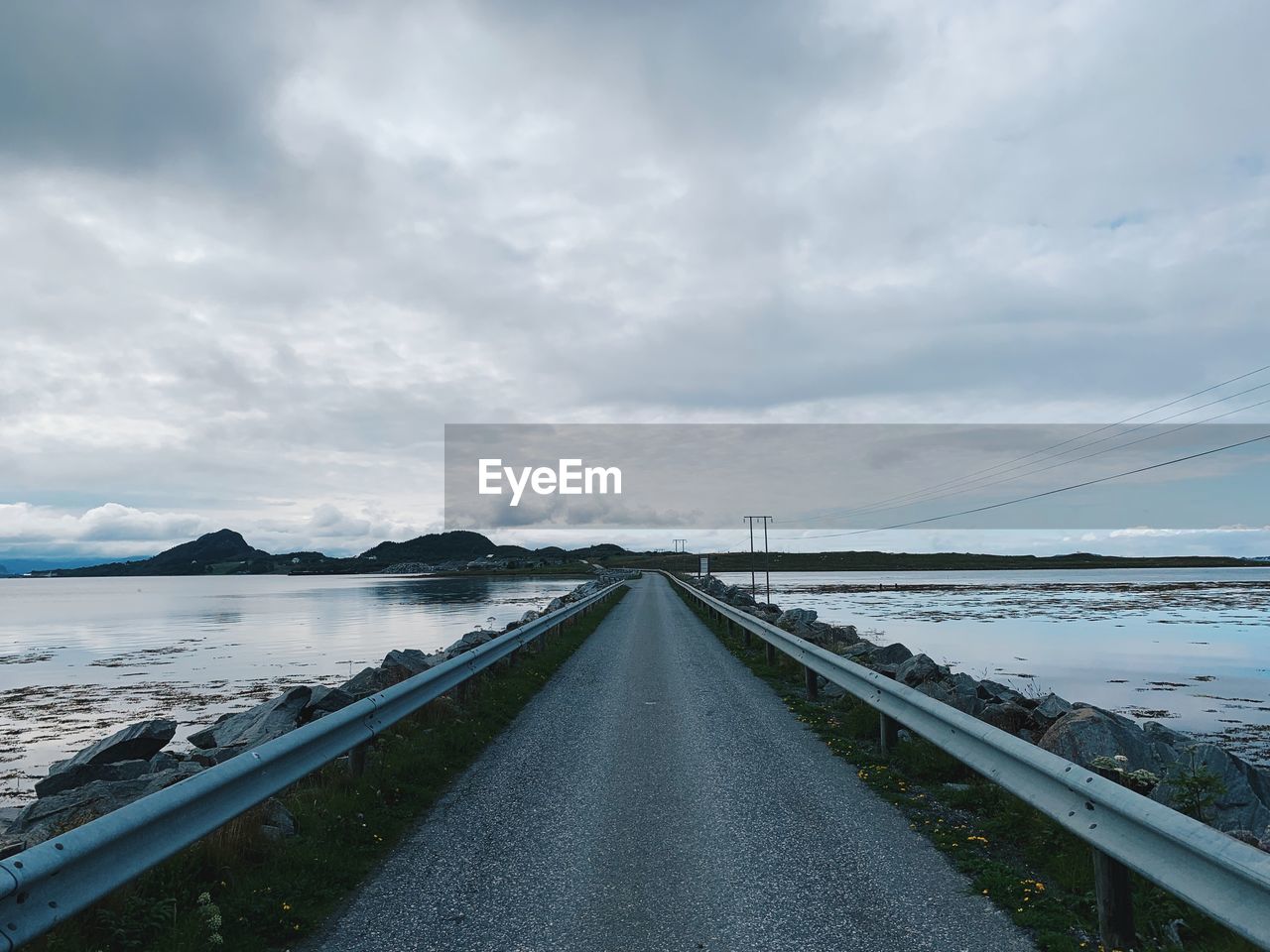 Empty and endless road in the middle of a nordic landscape, seashore, horizon over land and islands 