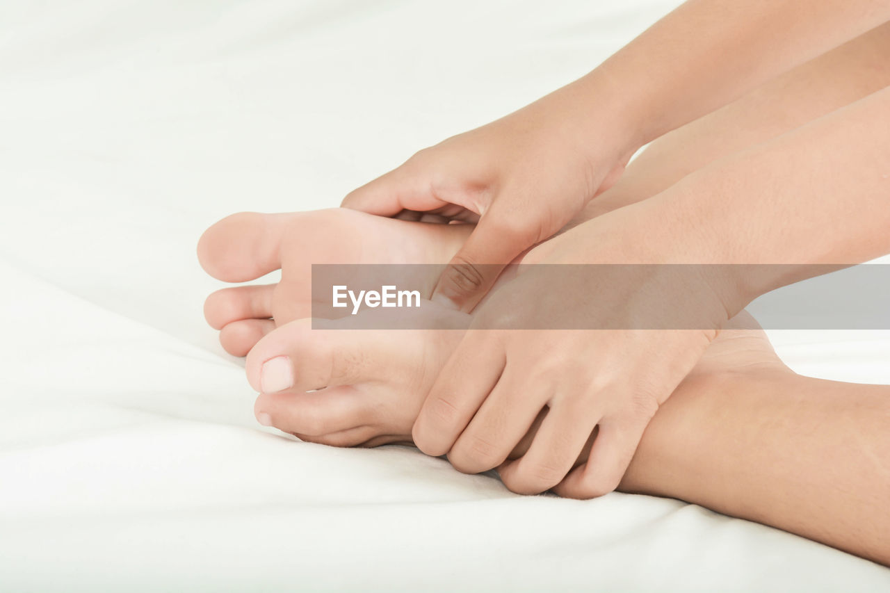 CLOSE-UP OF WOMAN HAND WITH TATTOO ON BED