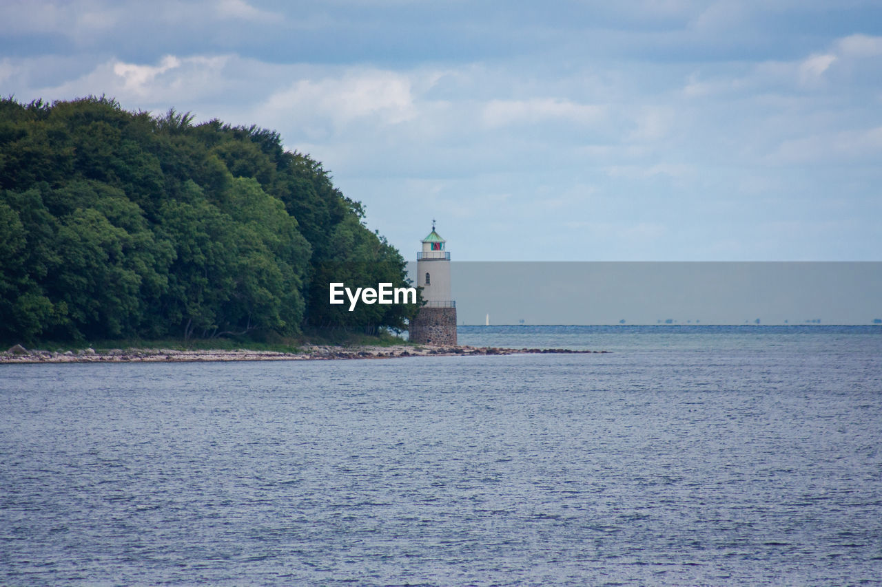 LIGHTHOUSE BY SEA AGAINST BUILDINGS