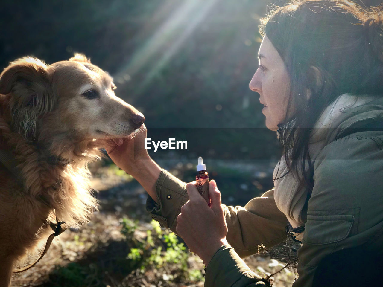 Side view of woman giving medicine to dog