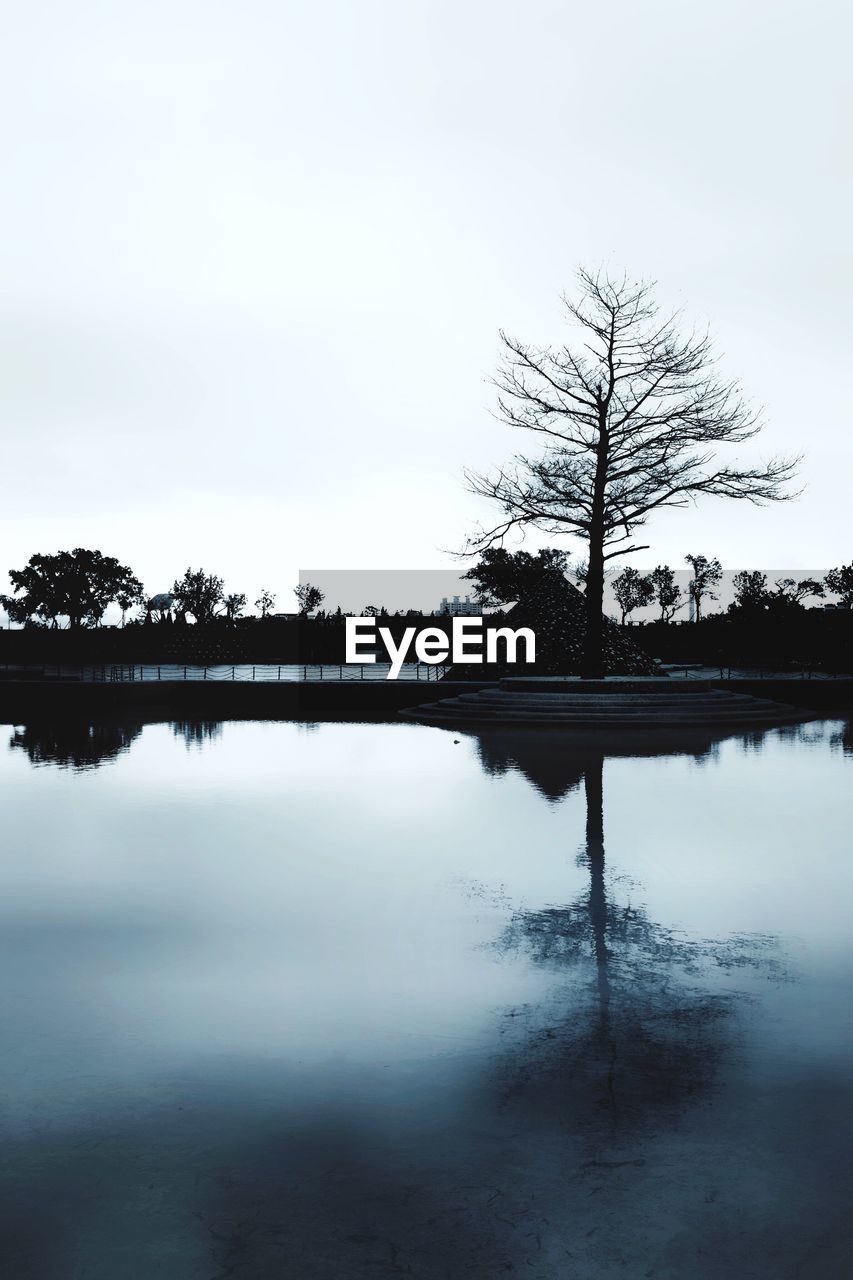 REFLECTION OF TREE ON LAKE AGAINST SKY