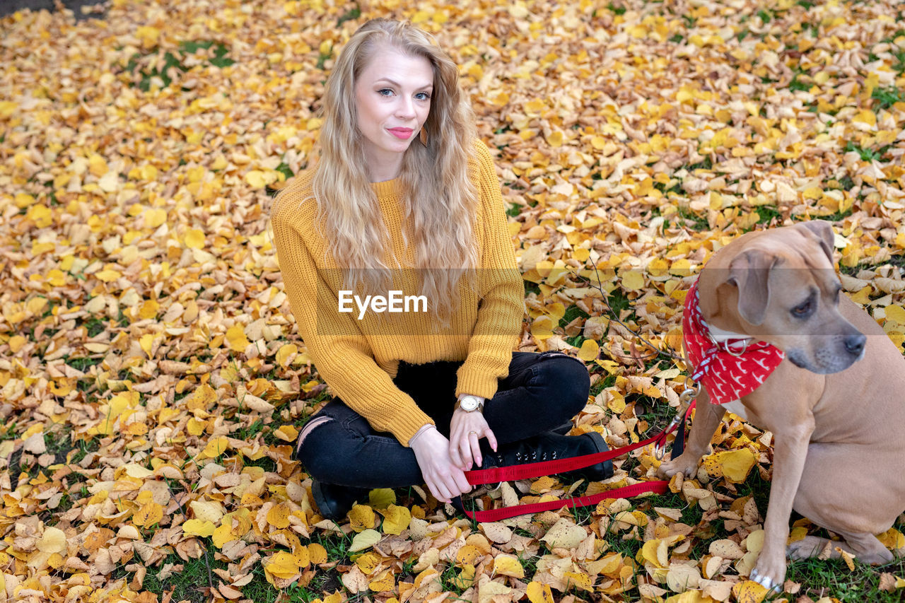 PORTRAIT OF TEENAGE BOY WITH DOG DURING AUTUMN