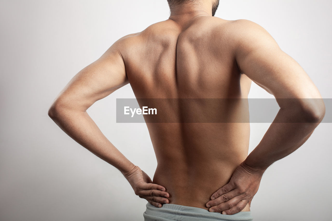 studio shot, arm, adult, muscular build, one person, undergarment, indoors, rear view, strength, wellbeing, men, lifestyles, young adult, exercising, standing, human muscle, gray background, back, gray, athlete, body conscious, bodybuilding, hand, clothing, vitality, cut out, sports, portrait