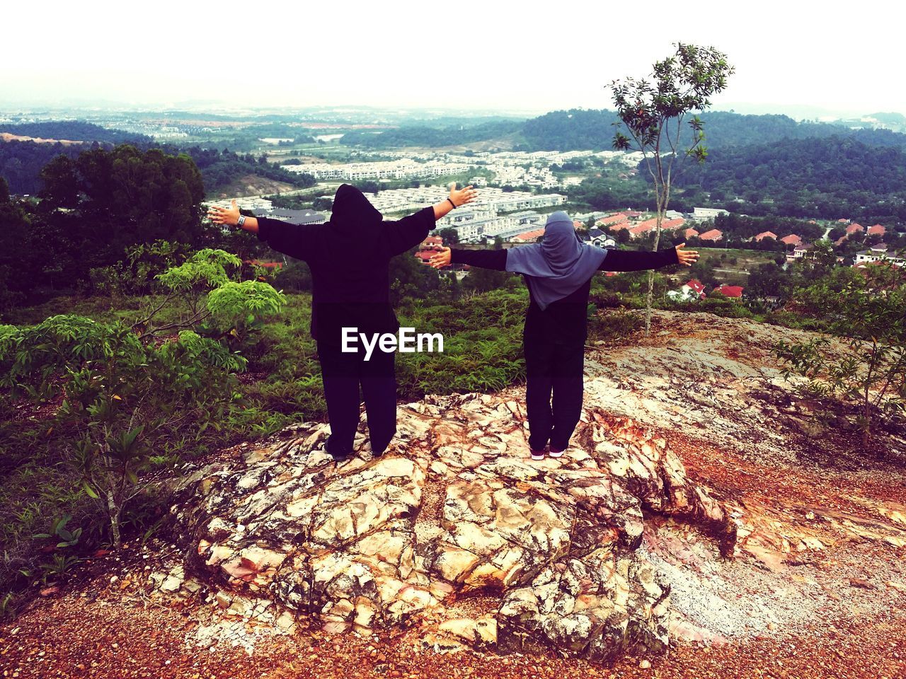 REAR VIEW OF MAN AND WOMAN STANDING BY TREE