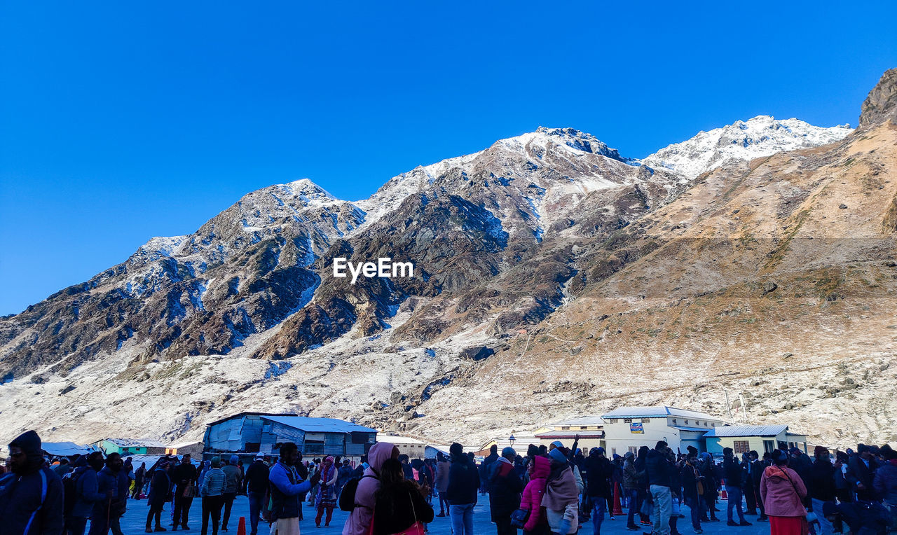 People on mountain against clear blue sky kedarnath temple