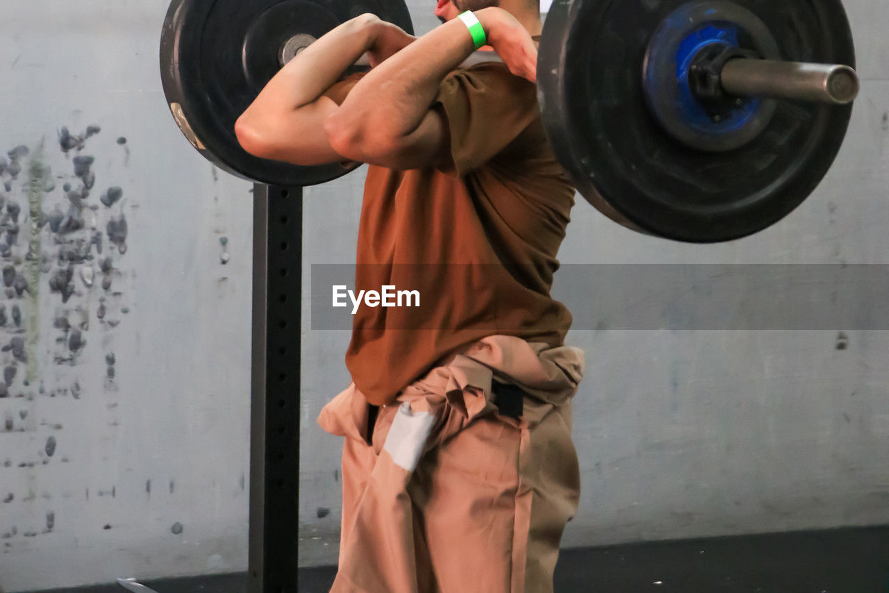 exercising, barbell, strength, sports, sports training, adult, one person, weight, muscular build, lifestyles, gym, weight training, weightlifting, determination, vitality, athlete, clothing, sports equipment, wellbeing, men, indoors, challenge, holding, overhead press, young adult, strength training, heavy, sports clothing, picking up, motivation, powerlifting, standing, activity, person, cross training, arm, leisure activity, concentration, bodypump, bodybuilding, deadlift