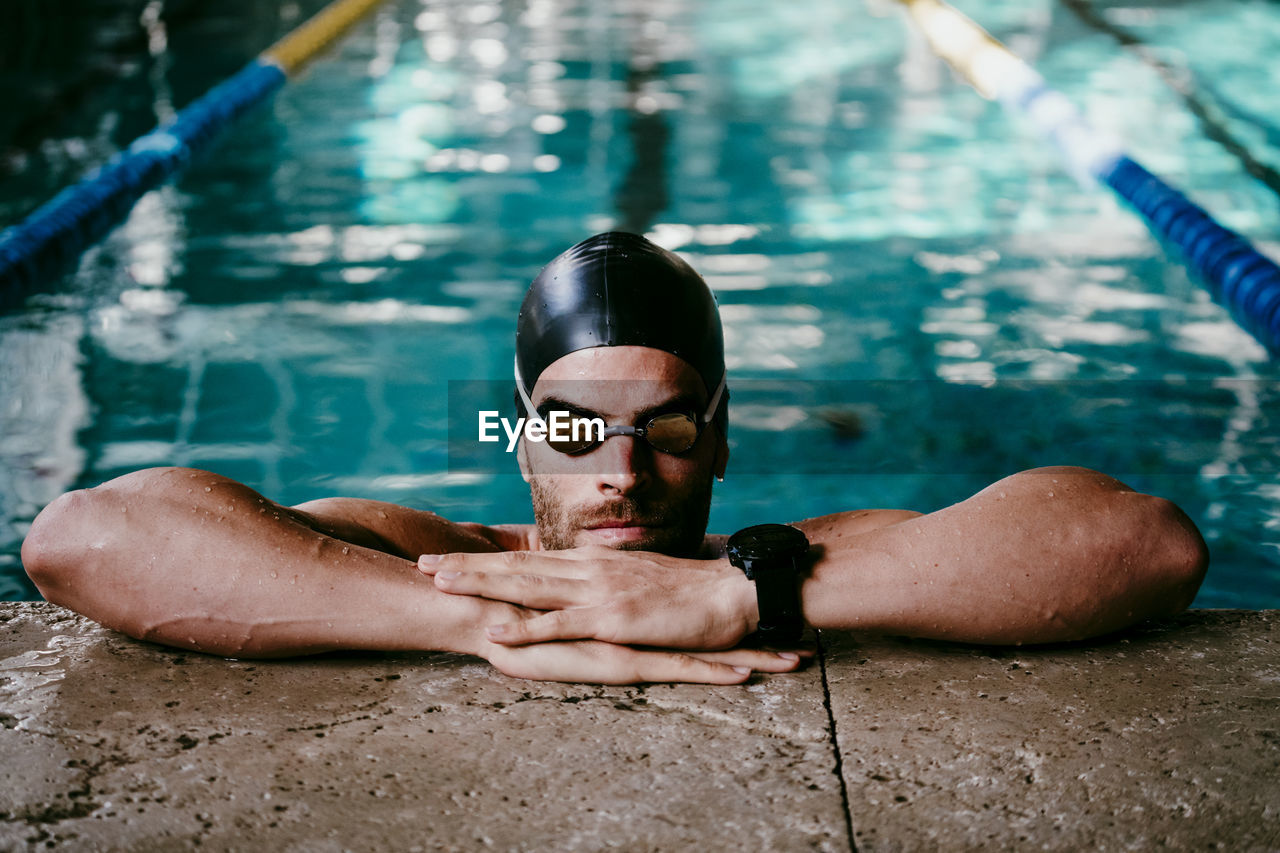 Professional male swimmer leaning at poolside