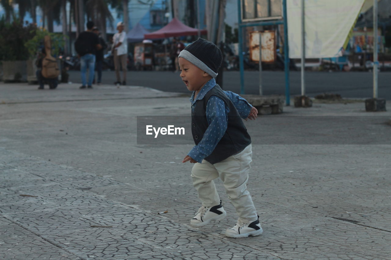 Full length of cute baby boy walking on street in city