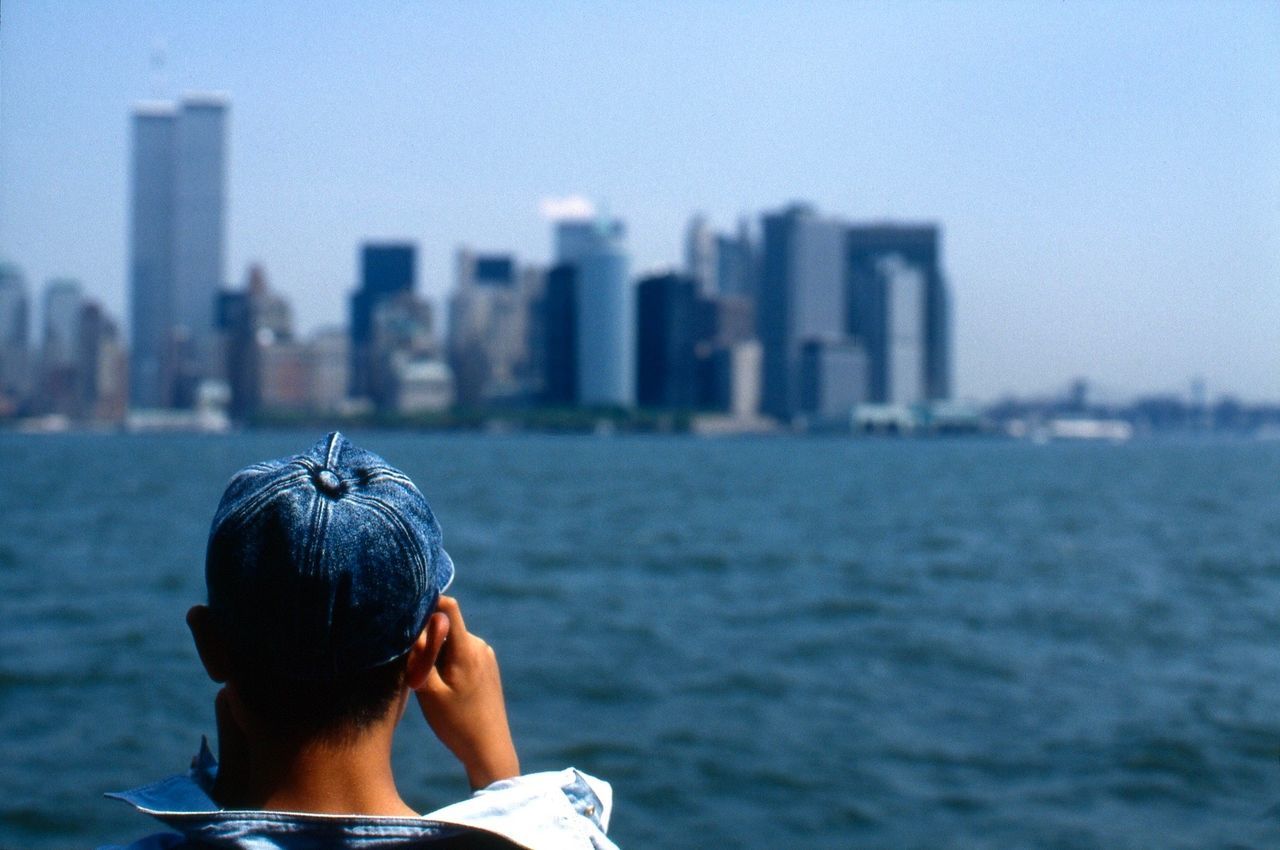 Rear view of man looking at east river by cityscape against sky