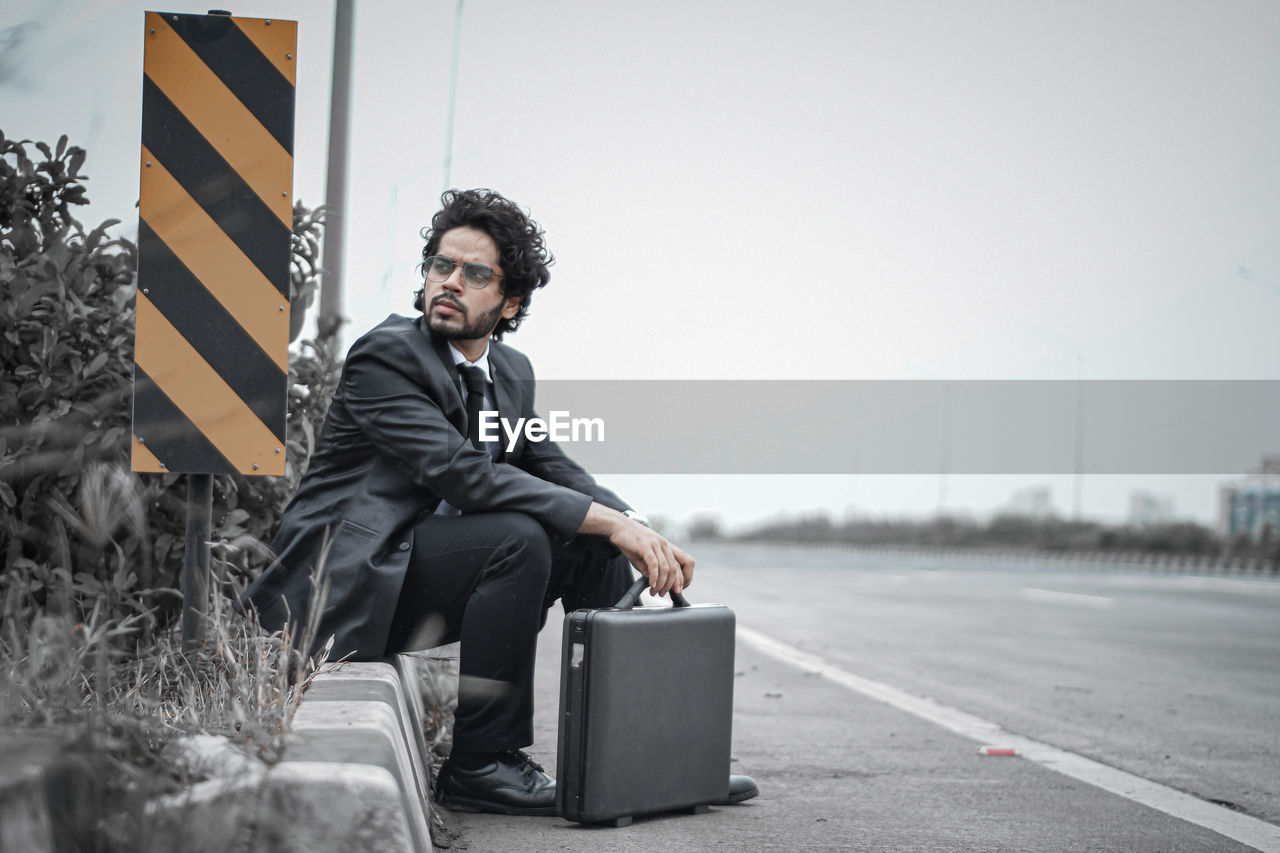 portrait of young man sitting on street