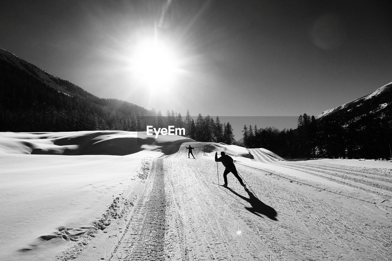 Silhouette people skiing on snow covered mountain
