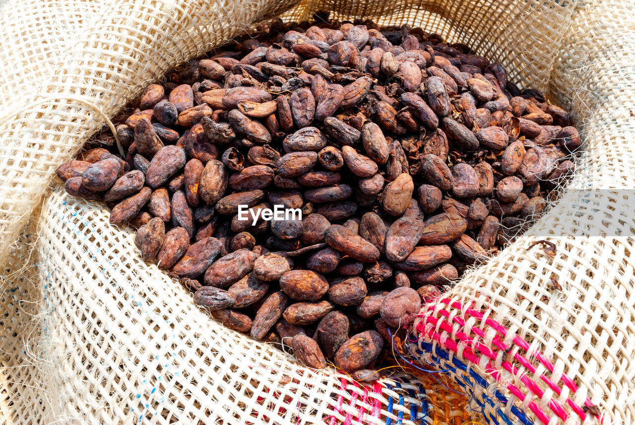 High angle view of freshly dried cocoa beans in rustic jute bags to transport