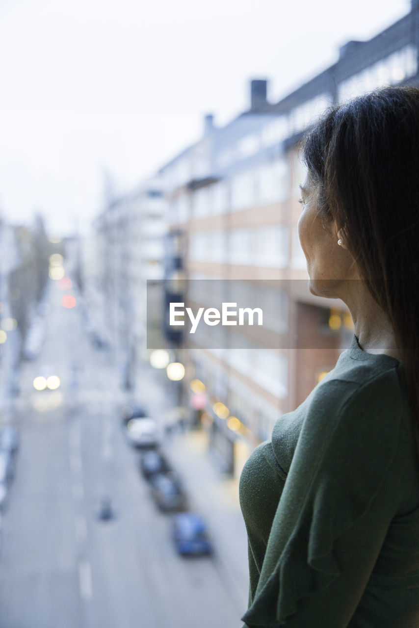 Woman looking through window at street