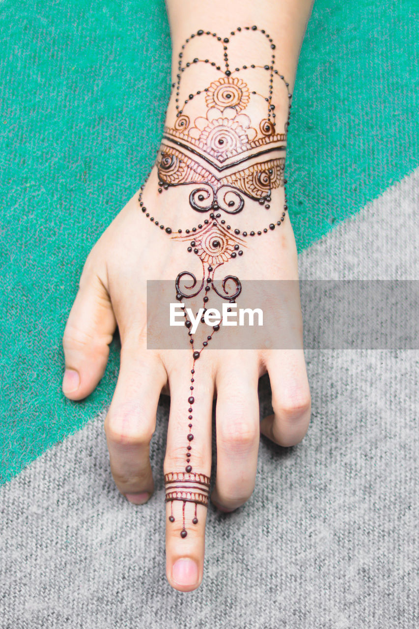 CLOSE-UP OF WOMAN HAND WITH TATTOO ON HUMAN HANDS