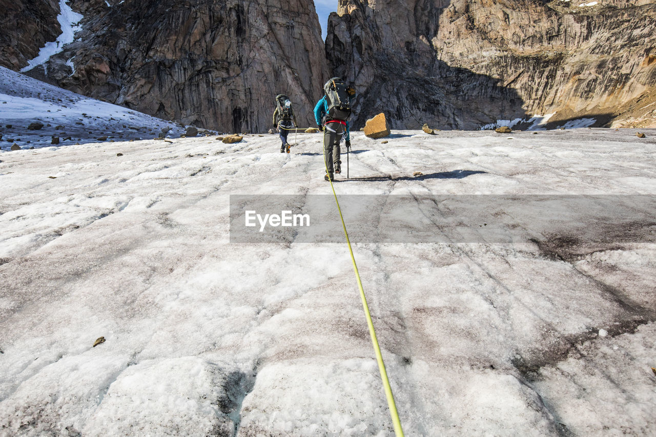 Climbers approaching mountain summit, baffin island.