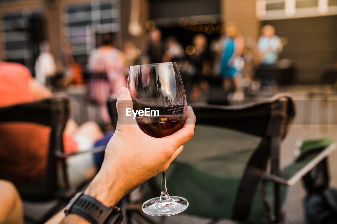 MIDSECTION OF WOMAN HOLDING WINE GLASS AT RESTAURANT AT BAR