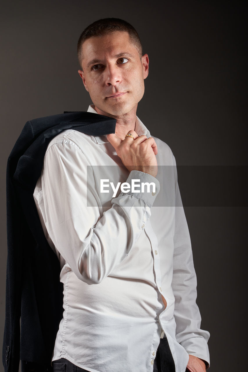 one person, studio shot, portrait, adult, formal wear, looking at camera, indoors, men, young adult, clothing, tuxedo, outerwear, sleeve, waist up, black background, standing, front view, white, photo shoot, three quarter length, person, collar, serious, cut out, gray, emotion