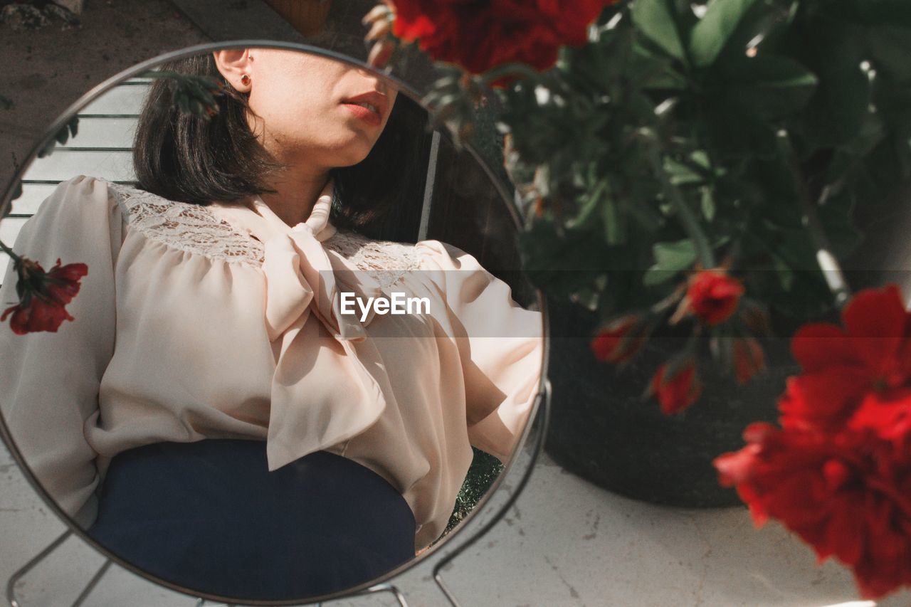 Young woman looking down while sitting on plant