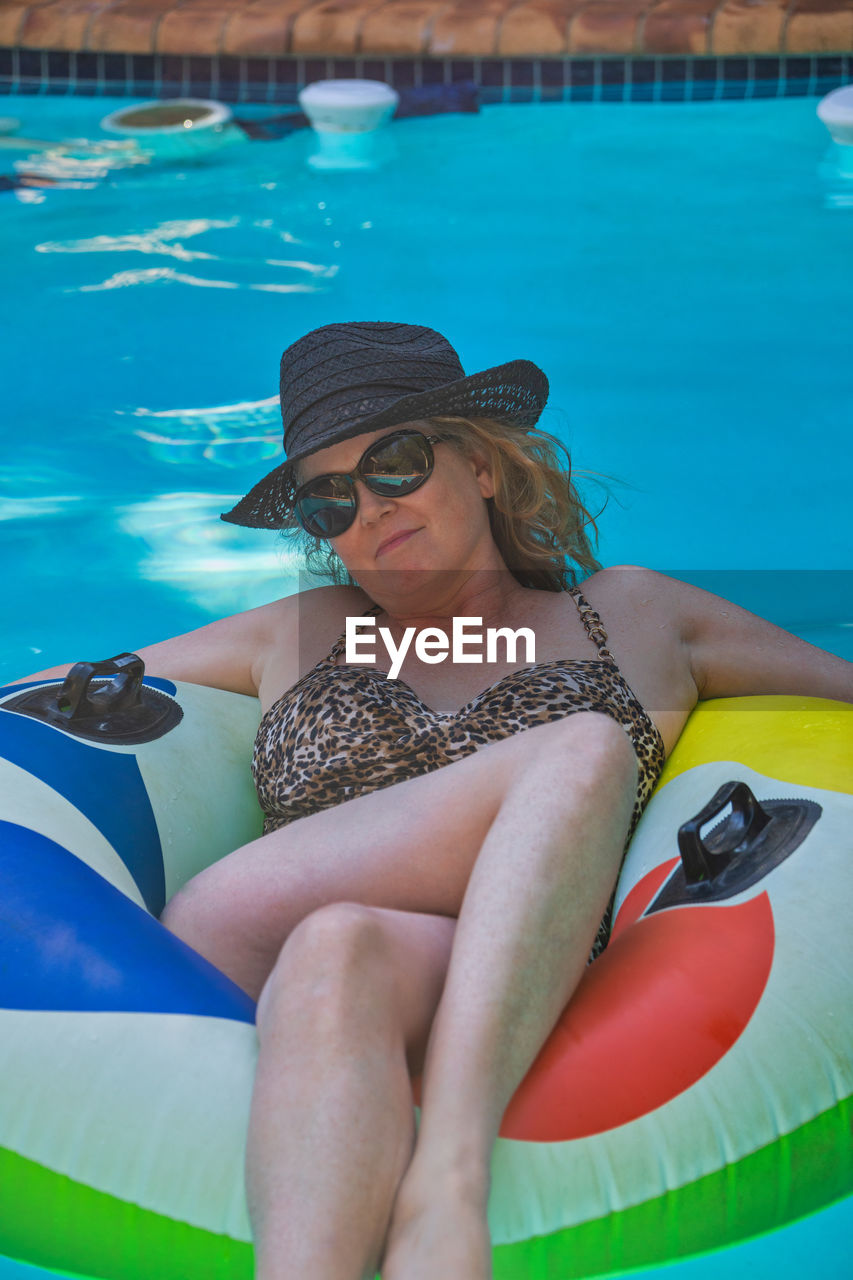 WOMAN SITTING BY SWIMMING POOL