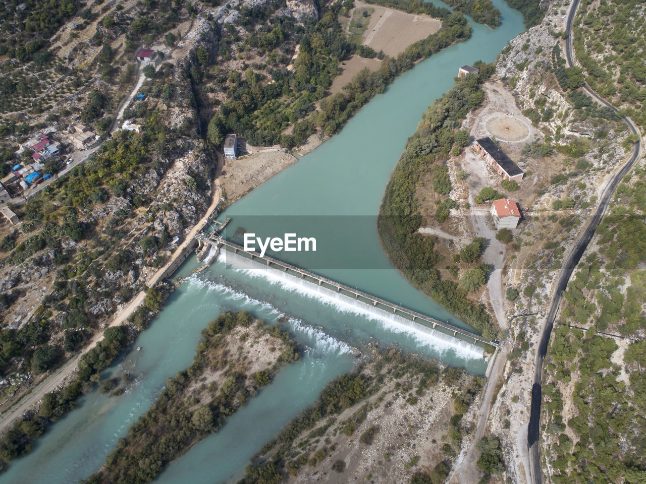 Dam at the mountain river and river island. aerial view