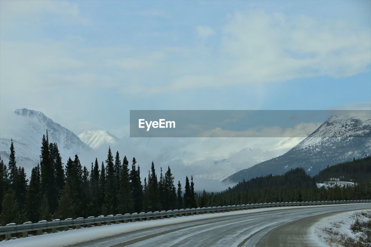 ROAD BY SNOWCAPPED MOUNTAINS AGAINST SKY DURING WINTER