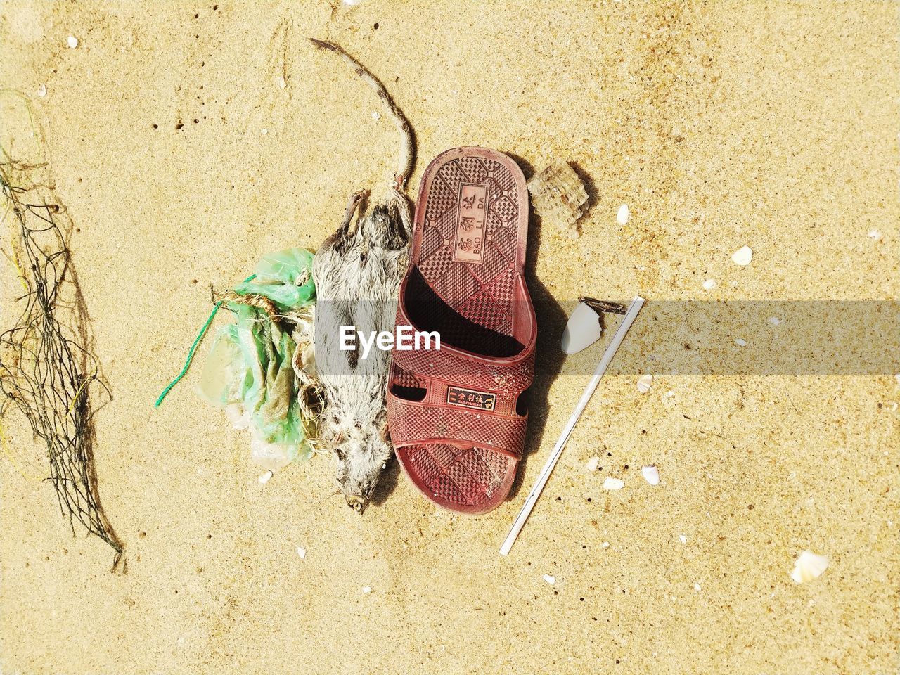 HIGH ANGLE VIEW OF BROKEN SHOE ON SAND