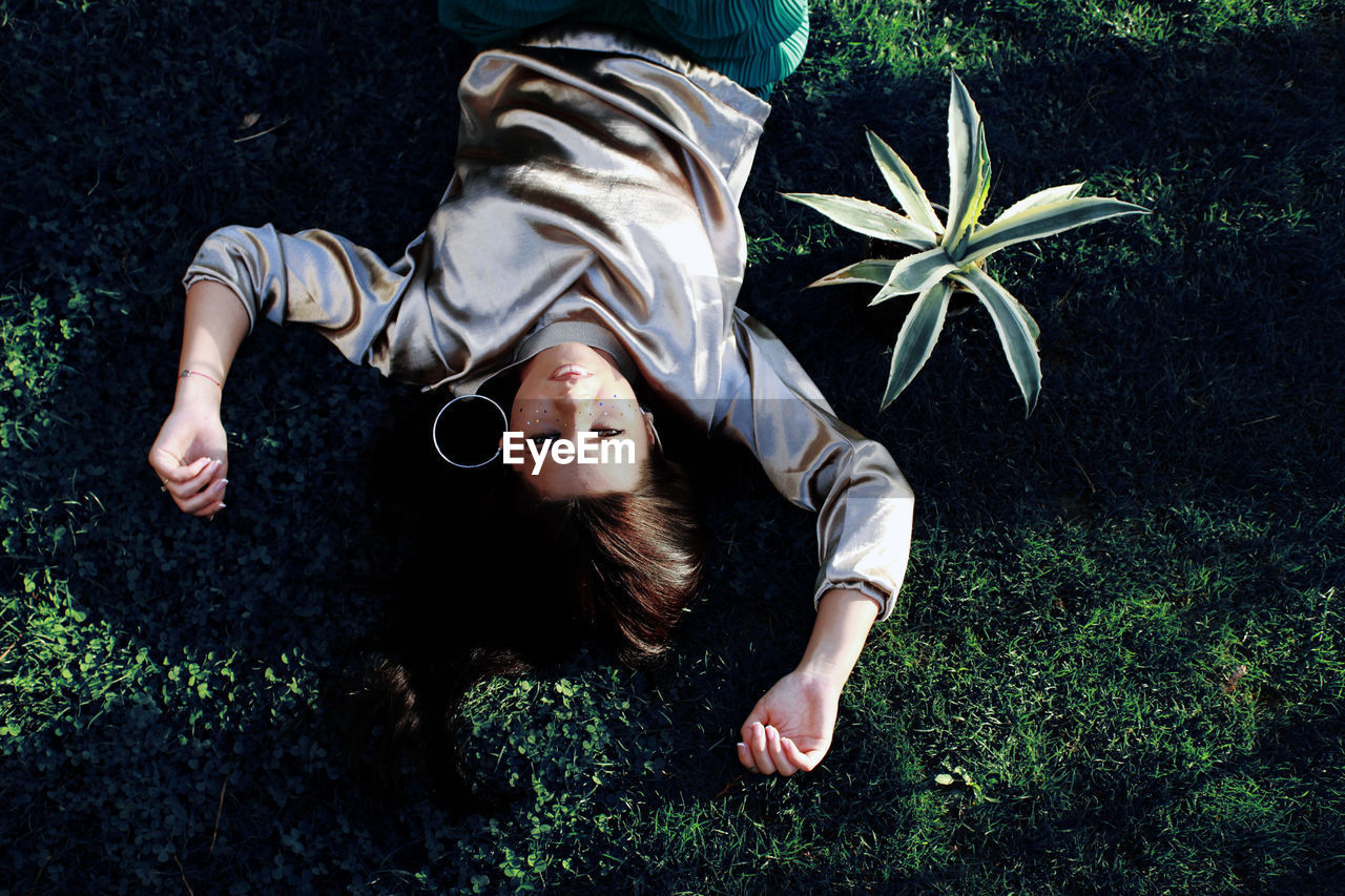 High angle portrait of young woman lying on grass