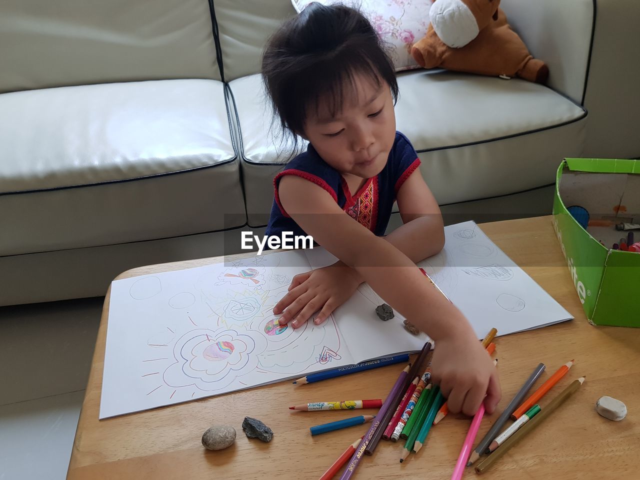 High angle view of girl drawing in book on table at home